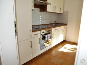 a kitchen with white cabinets and a sink at Ferienwohnung Koch Thurgauer Weg in Reichenau +4 photos