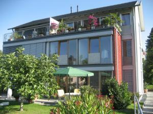 a building with a table and an umbrella in front of it at Ferienwohnung Koch Thurgauer Weg in Reichenau