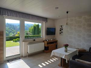 a living room with a table and a large window at Haus Nietmann Ferienwohnung 1 in Altenau