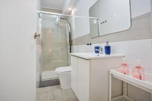 a white bathroom with a shower and a toilet at Las Américas Seafront - Free Wi-fi in Playa de las Americas +25 photos