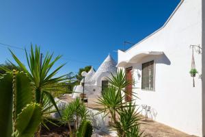 a white house with palm trees in front of it at Trullo Nunuccio in Ceglie Messapica