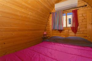a bedroom with a pink bed in a wooden cabin at Pink Pod in Saint-André