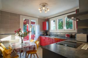 a kitchen with red cabinets and a table with yellow chairs at Au printemps Japonais in Pierre-Châtel