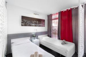 two beds in a room with red curtains at Estudio Yumbo Playa Del Ingles in San Bartolomé