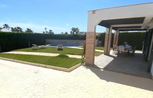 a garden with a patio and a swimming pool at Villa los Tres Menorca in Cala en Bosc