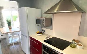 a small kitchen with a stove and a microwave at Villa los Tres Menorca in Cala en Bosc