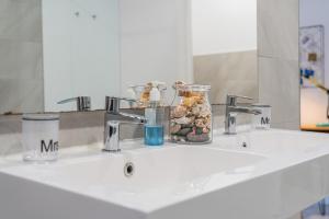 a bathroom sink with two faucets and a jar on it at Bonanova 20 in Palma de Mallorca +18 photos