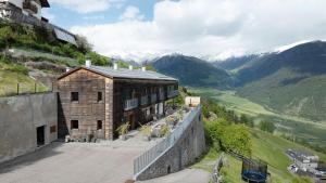a building on a hill with mountains in the background at Ansitz Röfen in Burgusio
