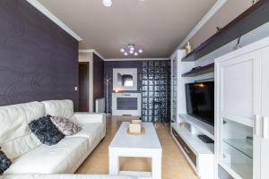 a living room with a white couch and a tv at Apartamento Brétema in Meaño
