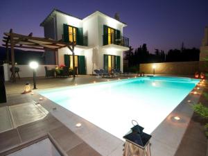 a large swimming pool in front of a house at Sami Beach Villas Nefeli in Karavomylos