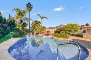 a swimming pool in a resort with palm trees at Calpe Vistas y Playa in Calpe
