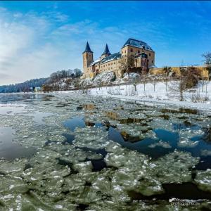 a castle in the middle of a river with ice at Ferienwohnung Rochlitzer Berg Blick in Seelitz