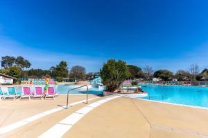 a swimming pool with chairs and a swimming pool at Mobilehome au bord de l'eau in Gastes