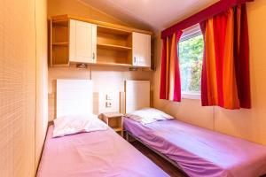 two beds in a small room with a window at Mobilehome au bord de l'eau in Gastes +17 photos