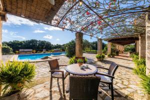 a patio with a table and chairs under a pergola at Finca Na Palada in Artá