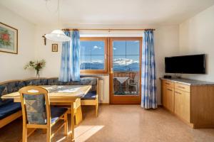 a living room with a dining room table and a television at Stücklhof Wohnung Rose in San Genesio Atesino