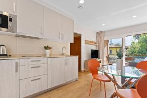 a kitchen with white cabinets and a glass table at 4 Terraza - Antilles sin jardin in Llanes +17 photos