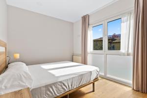 a white bedroom with a bed and a window at 4 Terraza - Antilles sin jardin in Llanes