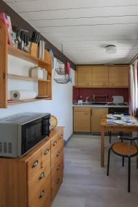 a kitchen with wooden cabinets and a table with a microwave at Ferienwohnungen Appelhof in Pellworm