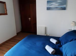 a bedroom with a blue bed with two towels on it at La Grange Aux Oiseaux in Beaulieu