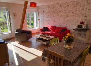 a living room with a red couch and a table at La Grange Aux Oiseaux in Beaulieu