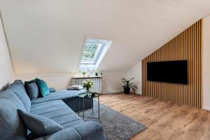 a living room with a blue couch and a tv at Dasensteinblick in Kappelrodeck