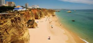 a group of people on a beach next to a cliff at Candirocha A8 in Portimão