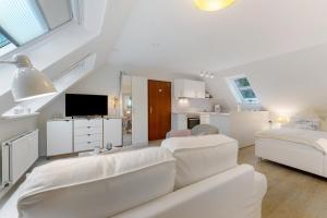 a white living room with a couch and a tv at Appartement Skagen in Glücksburg