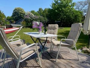 a group of chairs and a table with flowers on a deck at Ferienwohnung an der Schlei in Fleckeby