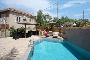 a swimming pool with chairs and umbrellas next to a house at Villa Dionysia Studio 9 in Alikanas