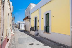 an alley with yellow and white buildings on a street at Donna Cesarina - Maison de Charme in Maruggio