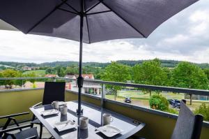 a table with an umbrella on a balcony at Ferienwohnung Mainaublick in Uhldingen-Mühlhofen