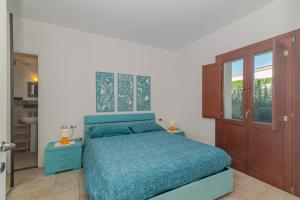 a bedroom with a bed with a blue comforter at Villetta Giardino e Piscina in Porto San Paolo +14 photos