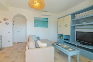 a living room with a couch and a tv at Villetta Giardino e Piscina in Porto San Paolo