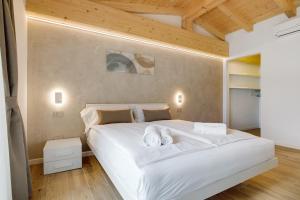 a bedroom with a large white bed and wooden ceilings at Jacky's Apartments in Limone sul Garda