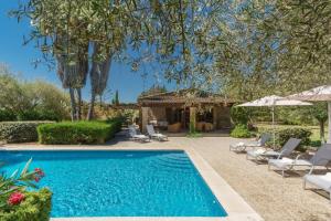 a swimming pool in a yard with chairs and umbrellas at Llangana in Pollença