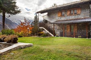 a stone house with a staircase in a yard at Piccolo Paradiso in Cogne