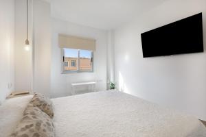 a white bedroom with a bed and a flat screen tv at Salitre in Las Eras