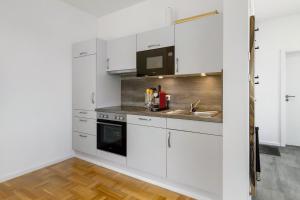 a kitchen with white cabinets and a sink at Studio im Grünen und Bodenseenähe in Rielasingen-Worblingen