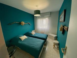 a bedroom with a bed and a blue wall at Le Lodge d Angèle in Honfleur