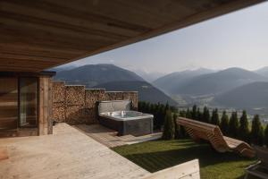 a hot tub on a deck with a view of mountains at Rueper Hof Chalet Dolomit in Valdaora +6 photos