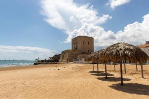 a beach with some straw umbrellas and a building at Casa Luna in Pozzallo