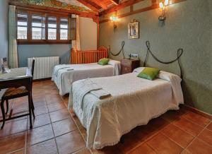 a bedroom with two beds and a table and a desk at El Lagar in Canalejas de Peñafiel