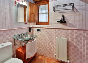 a pink tiled bathroom with a sink and a toilet at El Lagar in Canalejas de Peñafiel +23 photos
