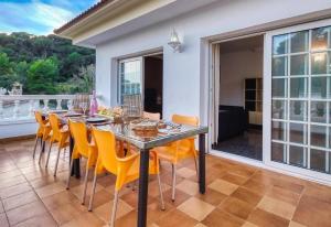 a dining room with a table and yellow chairs at Costacabana - Villa Rosa in Lloret de Mar