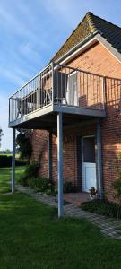 a brick house with a balcony on top of it at Fewo Sandbank in Pellworm