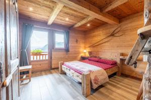 a bedroom in a log cabin with a bed and a window at Gite Les Clapières in La Giettaz