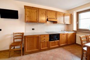 a kitchen with wooden cabinets and a tv on the wall at Chalet Anna Cigambola in Livigno +10 photos