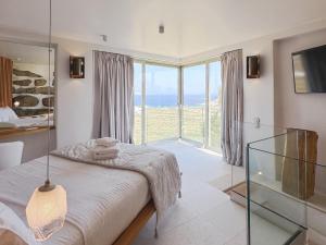 a bedroom with a bed and a large window at Alegria Mykonos 7 Suites in Kalafatis +35 photos