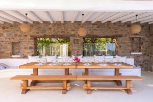 a dining room with a table and benches at Alegria Mykonos 7 Suites in Kalafatis